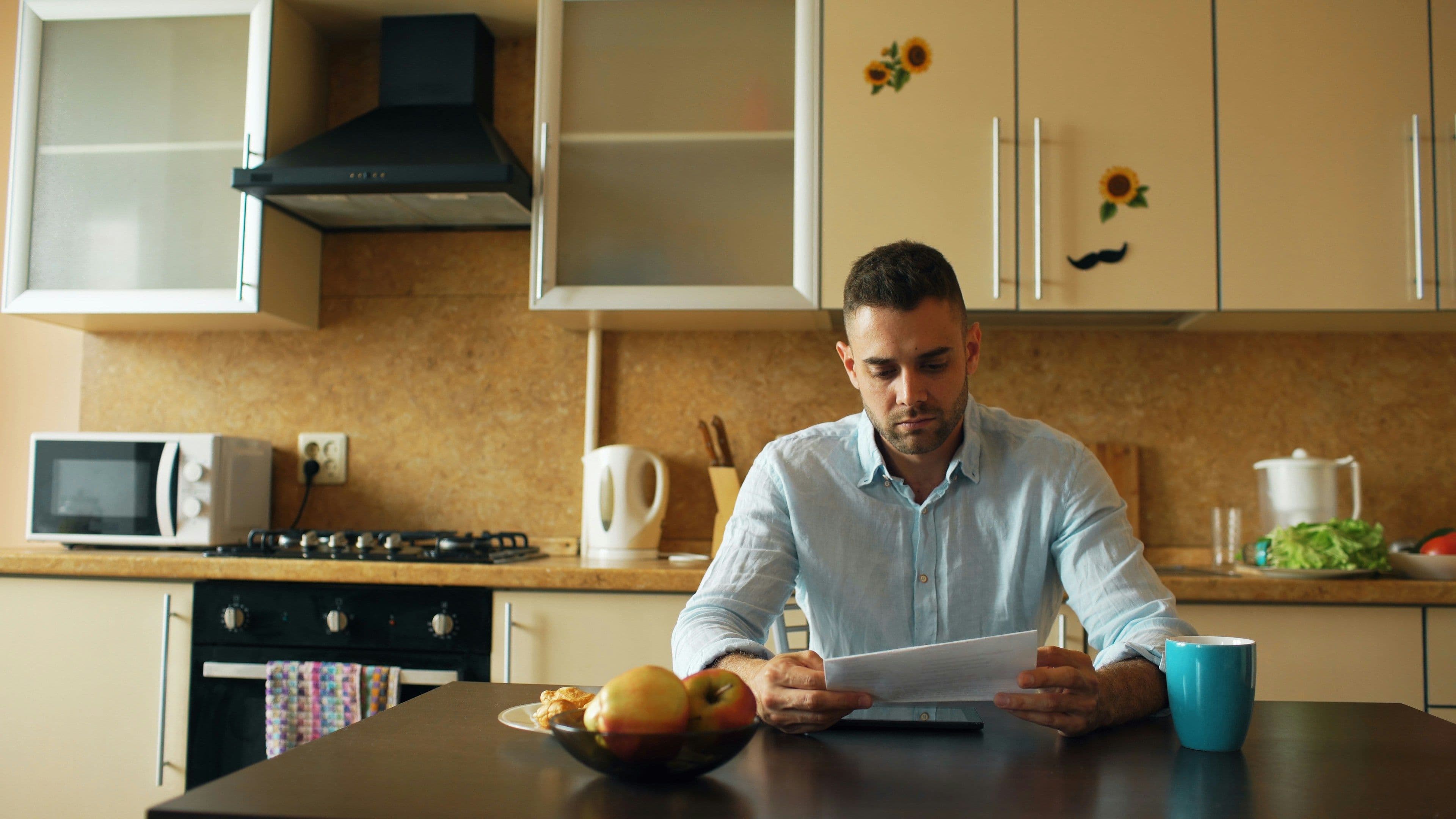 Man at kitchen table, looking at paperwork